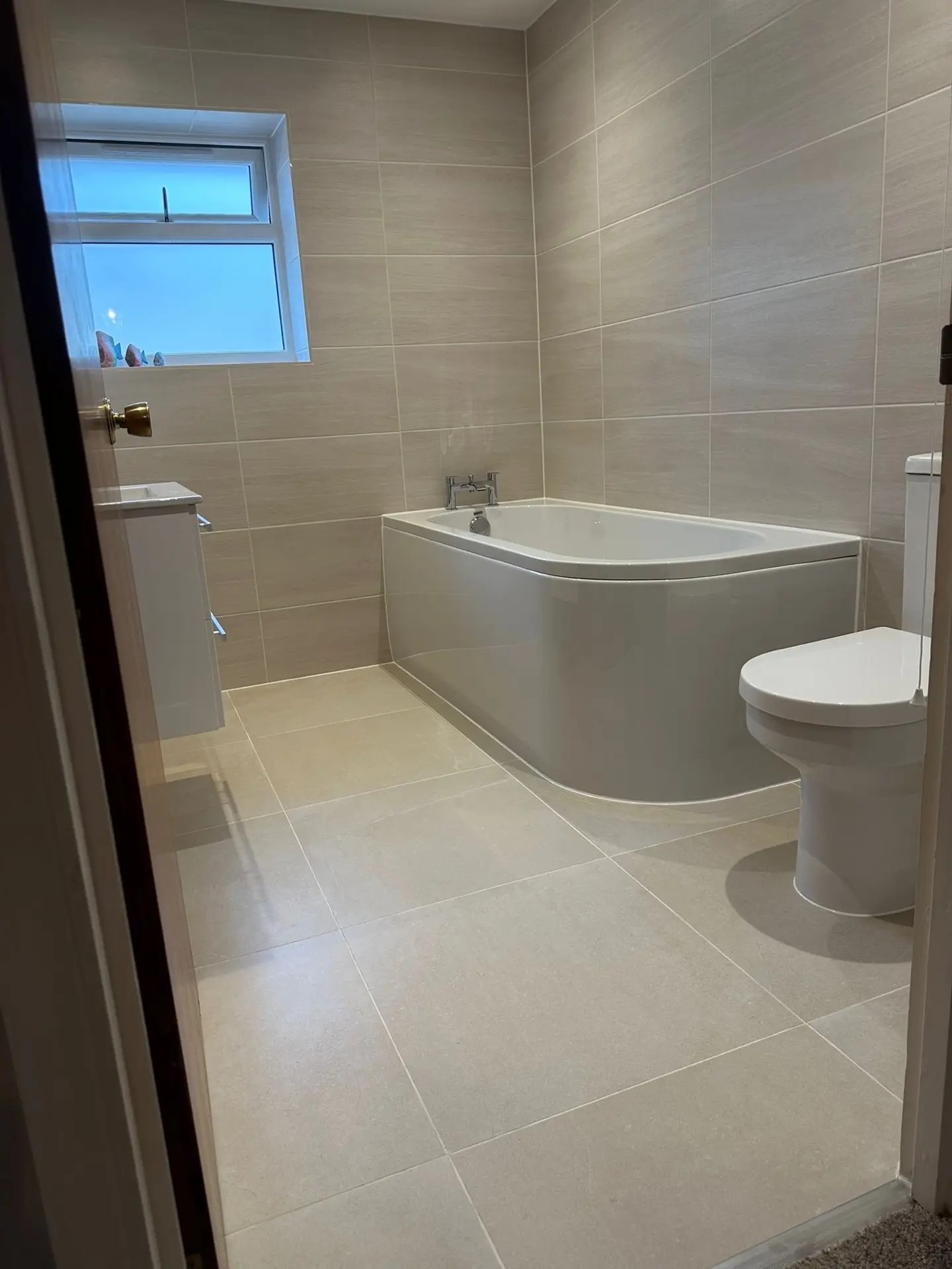 Completed bathroom with bath, WC and neutral tile finish