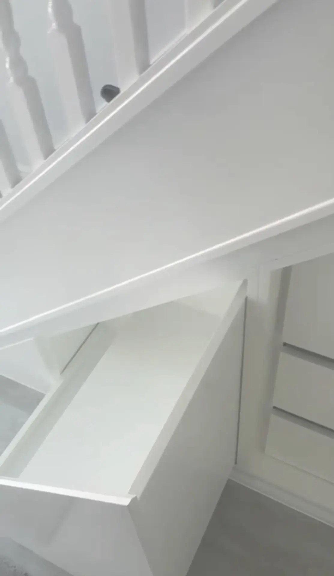 Under-stairs pull-out storage solution in white joinery