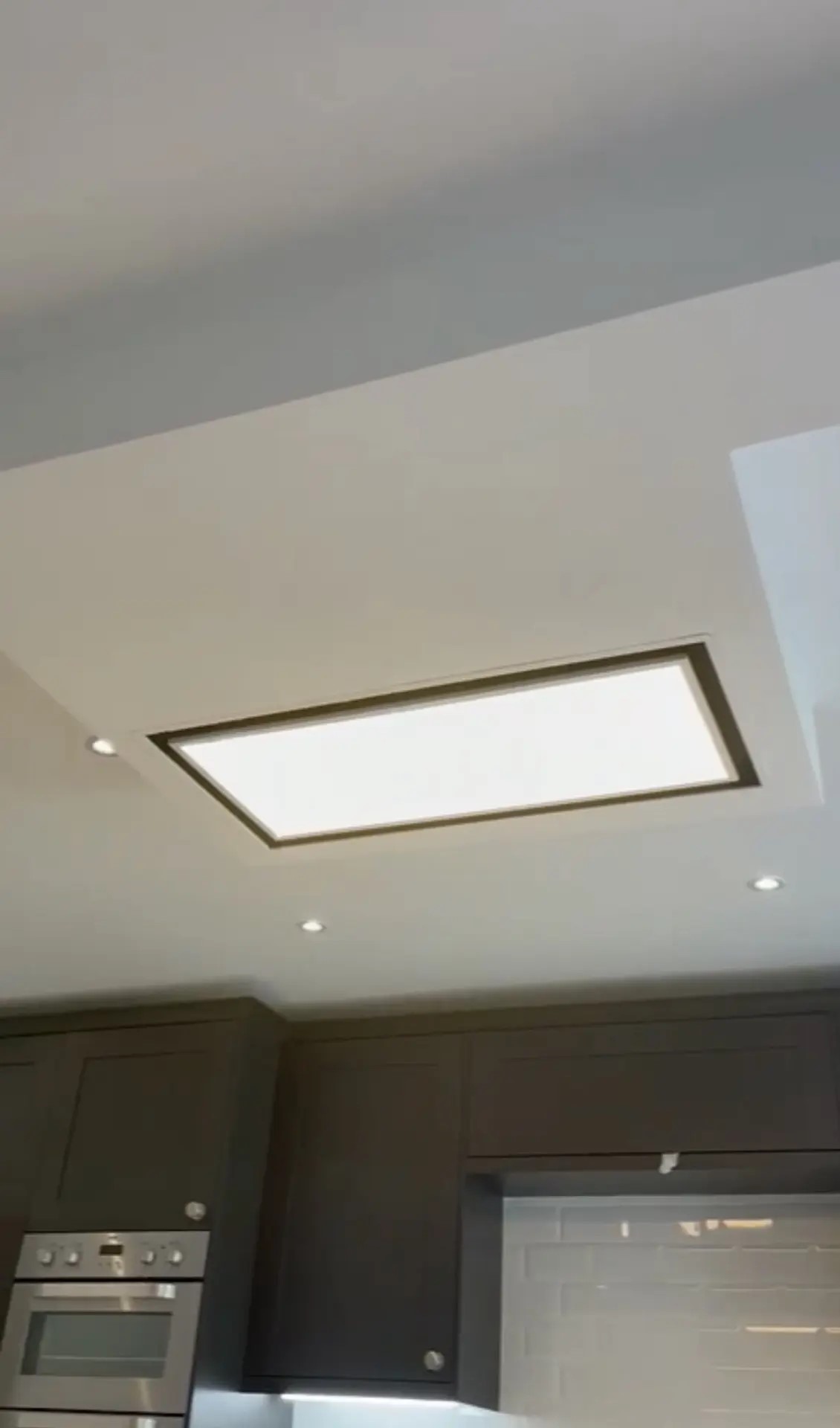 Kitchen ceiling detail with recessed lights and a large illuminated ceiling panel